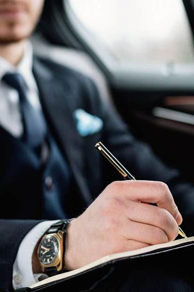 Young Businessman Writing In Notebook In Luxury Car
